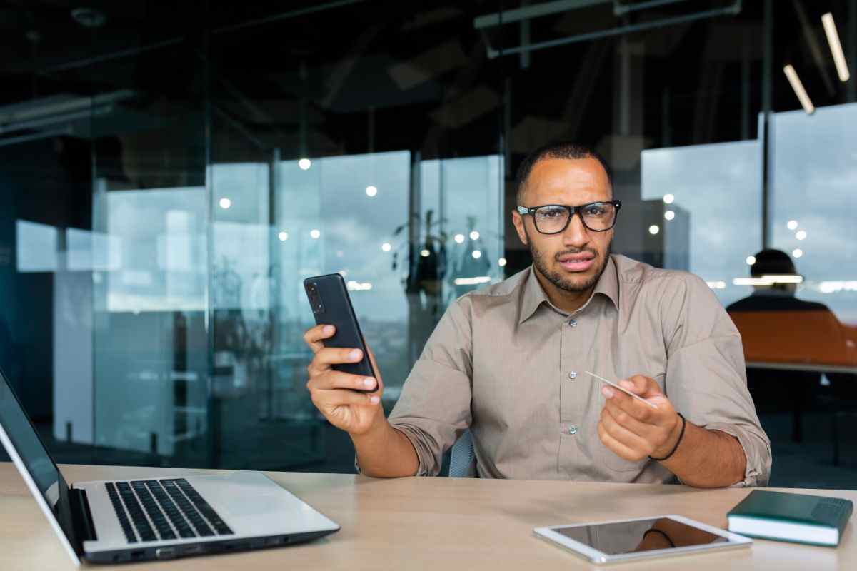 uomo con smartphone e bancomat in mano
