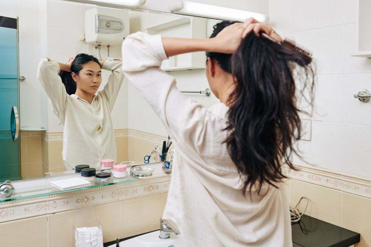 donna in bagno che sistema i capelli in una coda