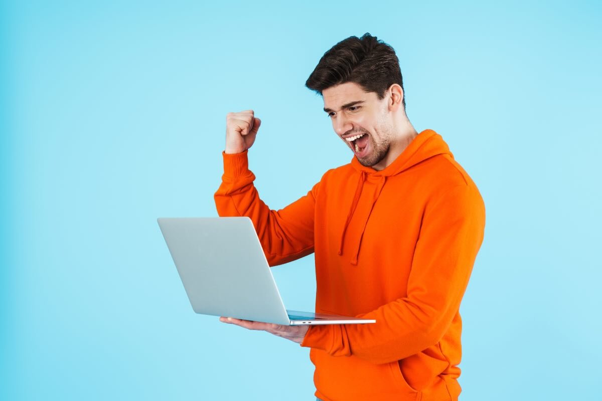 uomo felice al pc con felpa arancione