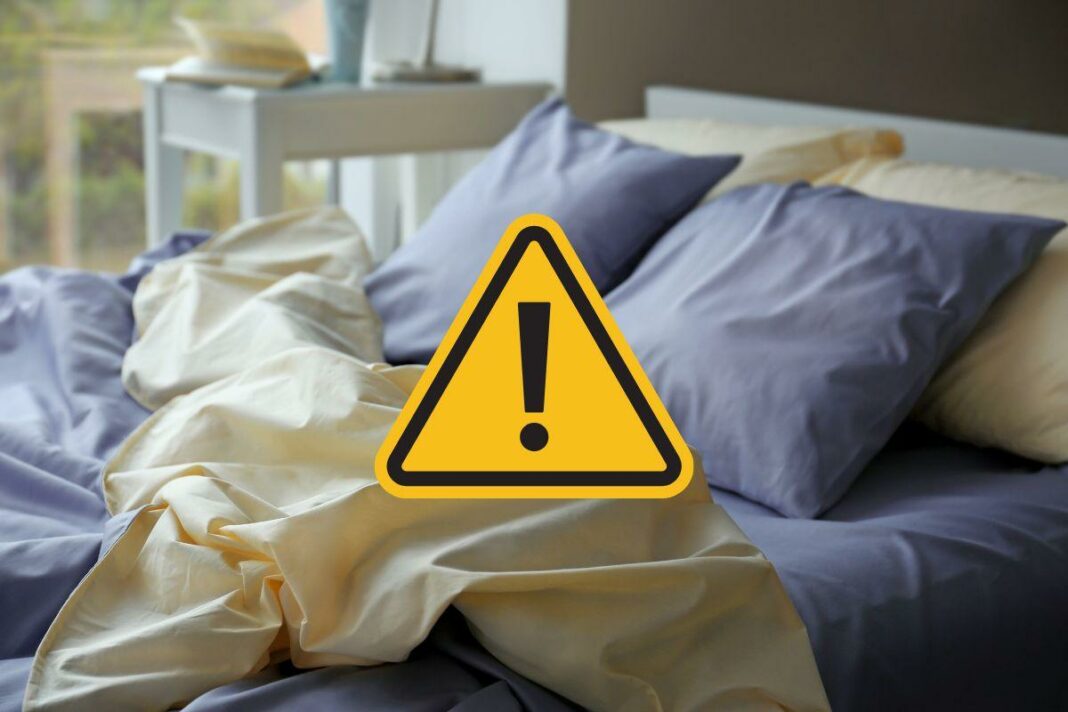 letto sfatto e segnale di pericolo giallo