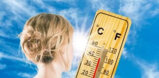 donna di spalle con chignon accanto ad un termometro per temperatura