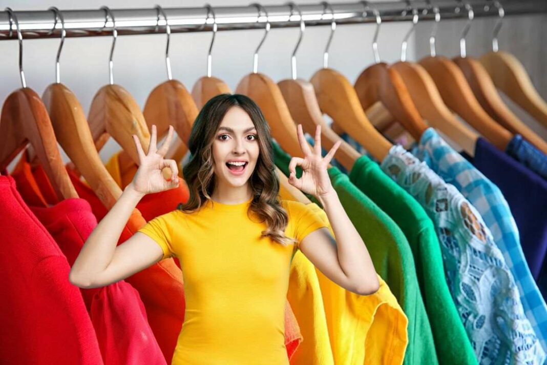 donna che fa ok e abiti colorati appesi