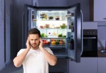 uomo che si tappa le orecchi e frigo aperto alle spalle