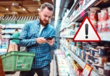 uomo al supermercato con cestino e segnale attenzione