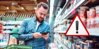 uomo al supermercato con cestino e segnale attenzione