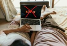 donna sul letto con mano su pc con netflix e x rossa