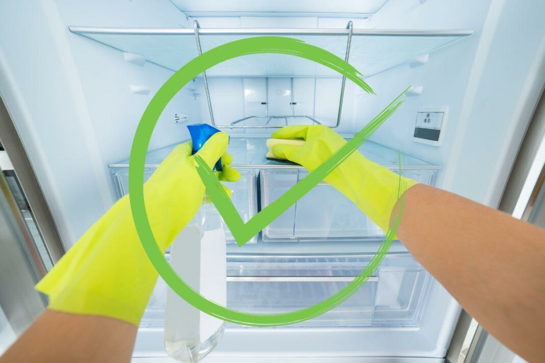 spunta verde su mani che puliscono il frigorifero
