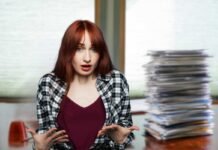 donna colpevole con capelli rossi e pila di documenti su scrivania