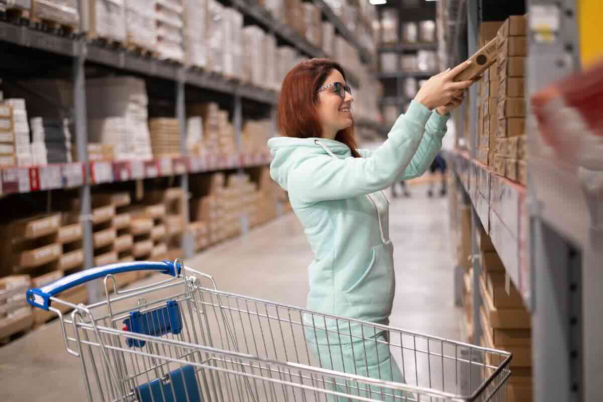 donna con tuta azzurra e carrello che sceglie mobili da ikea