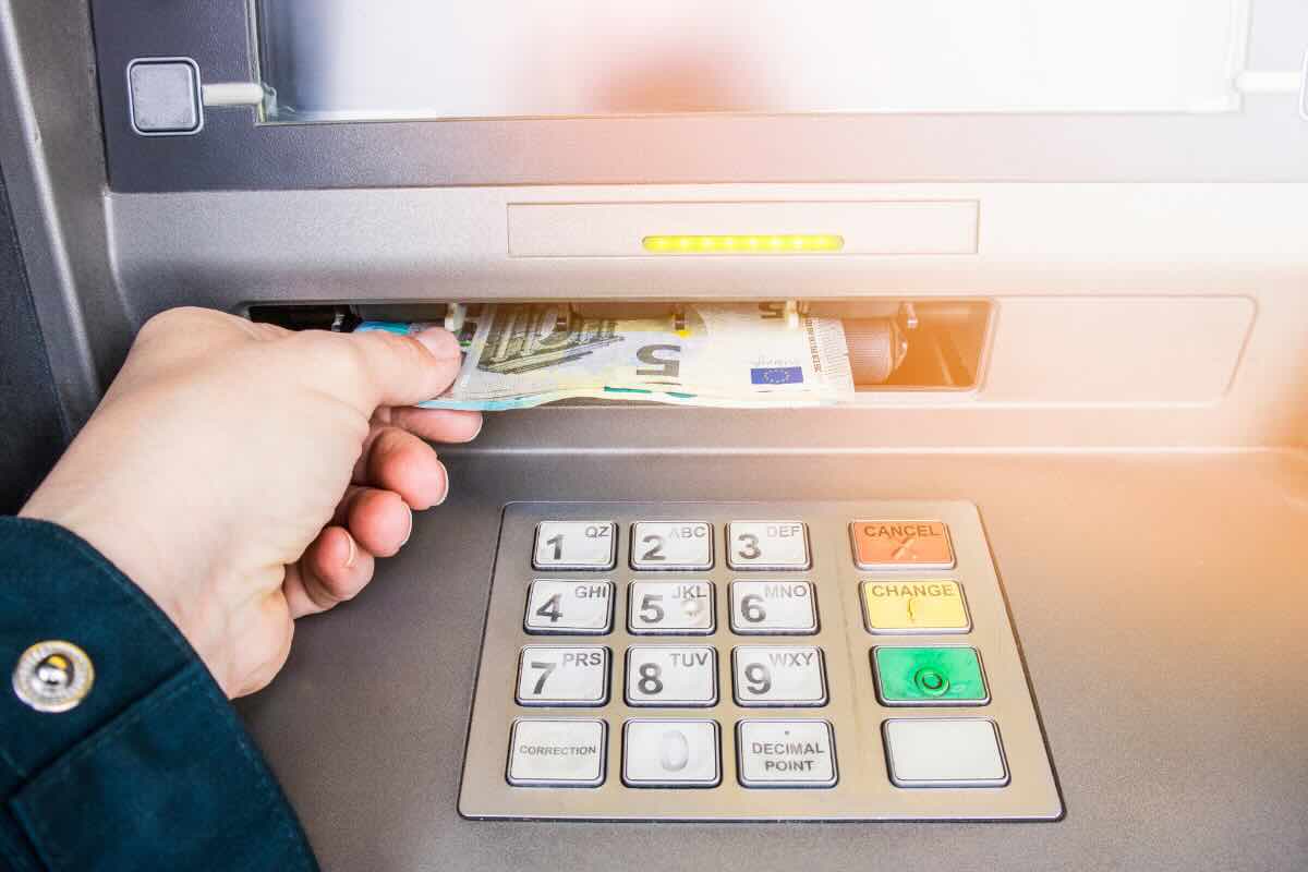mano che preleva banconota da ATM