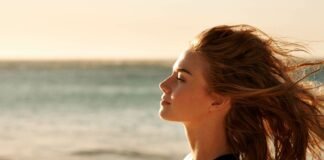 donna di profilo in riva al mare al tramonto