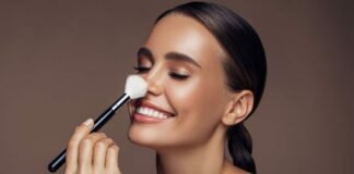 donna sorridente che si passa pennello da trucco sul naso