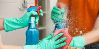 persona che pulisce specchio con spray e pezza