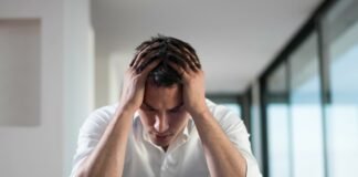 uomo amareggiato che legge su un tavolo