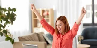 donna felice al pc con braccia alzate