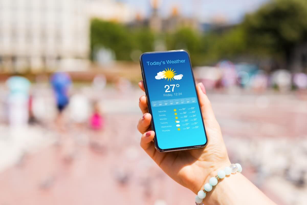 mano con smartphone con previsioni meteo