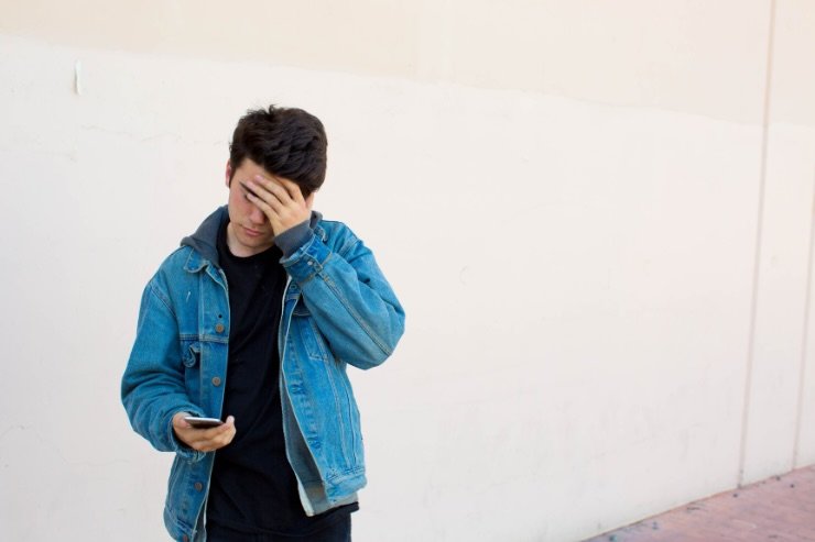 ragazzino triste con smartphone