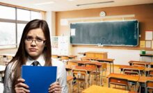 ragazza triste con occhiali e sfondo di una classe