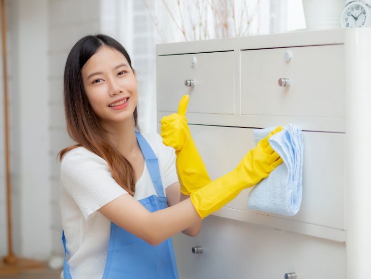 donna che pulisce cassettiera bianca