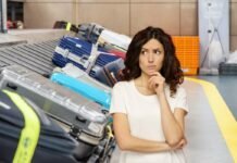 Sono un addetto ai bagagli nell’aeroporto e ti svelo cosa non dovresti mai fare con la tua valigia valigie sul rullo dell'aeroporto e donna che pensa