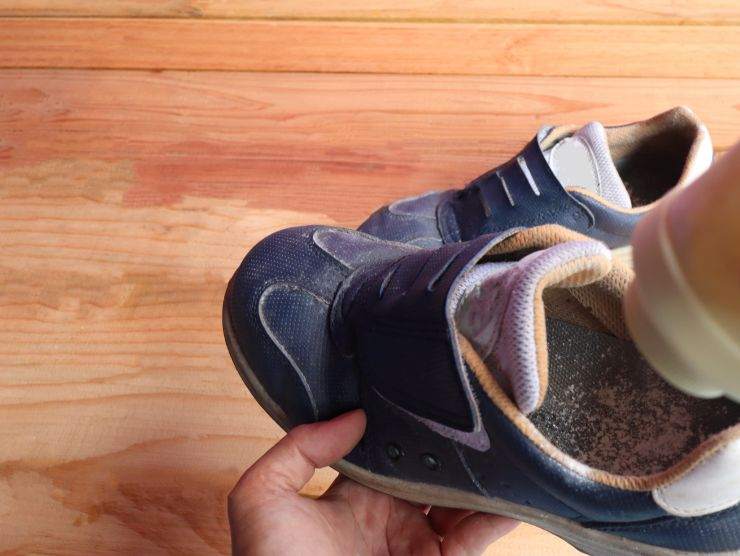 persona che mette polvere bianca nelle scarpe