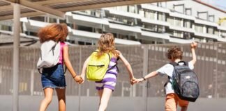 alunni con zaino che corrono dandosi le mani