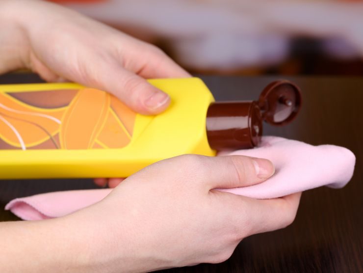 persona che versa prodotto su di un panno per togliere la polvere