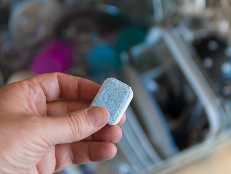 mano che mantiene una pasticca per lavastoviglie