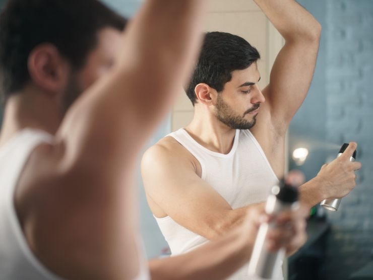 uomo che mette deodorante