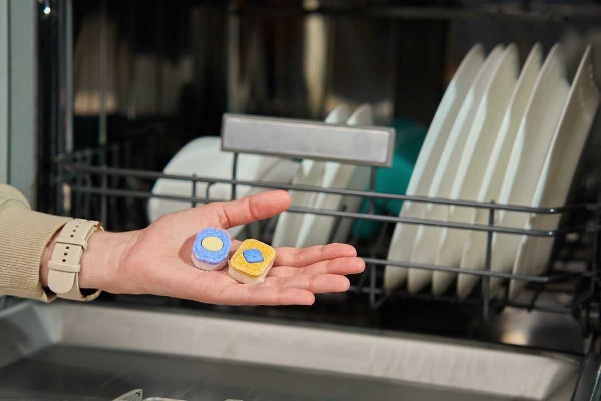 mano che ha nel palmo un paio di pasticche per la lavastoviglie