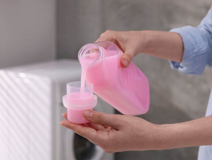 donna che versa ammorbidente nel tappo 