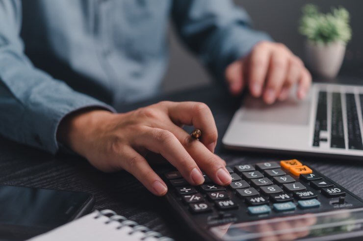 uomo con calcolatrice e pc