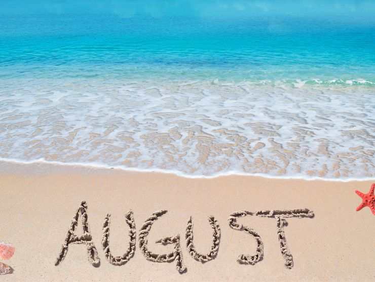 spiaggi e scritta agosto su sabbia