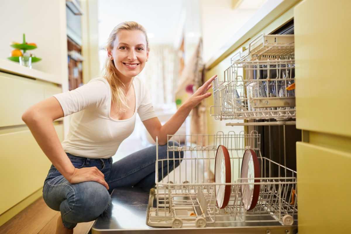 donna sorridente accanto alla lavastoviglie