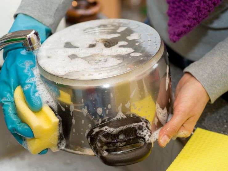 persona che pulisce pentola in acciaio