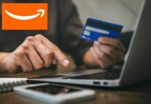 mano che digita su pc, carta e logo amazon