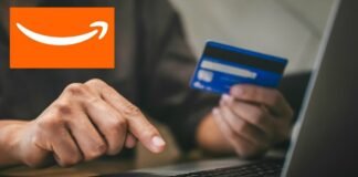 mano che digita su pc, carta e logo amazon
