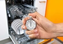 lavastoviglie aperta e carica e mano che impugna un cronometro