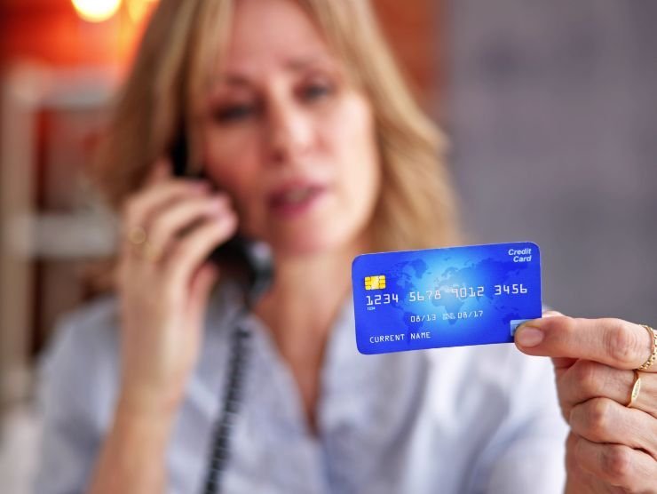donna che parla al telefono con carta di credito in mano