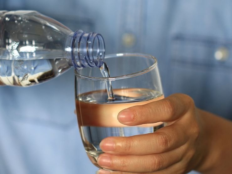 persona che riempie un bicchiere d'acqua