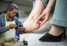 calzolaio che lavora e donna che mostra una vescica al piede fatta da una scarpa stretta