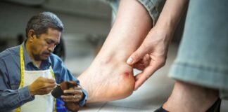 calzolaio che lavora e donna che mostra una vescica al piede fatta da una scarpa stretta