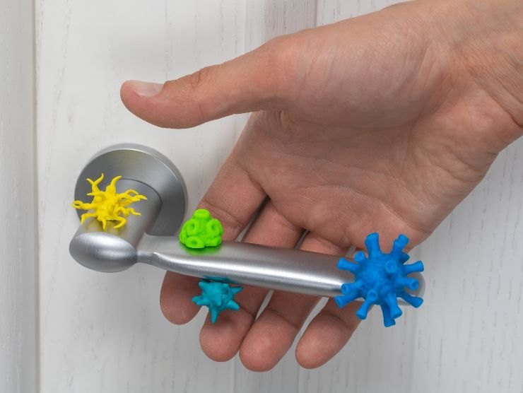 mano che tocca una maniglia della porta piena di germi