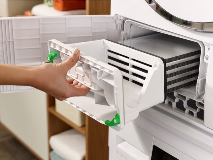 mano che afferra serbatoio dell'asciugatrice per svuotarlo