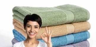 donna sorridente che fa ok e pila di asciugamani