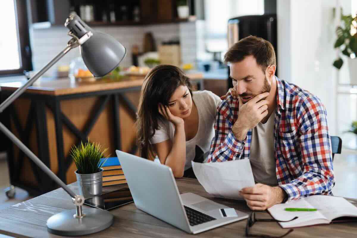 uomo e donna che guardano foglio e pc 