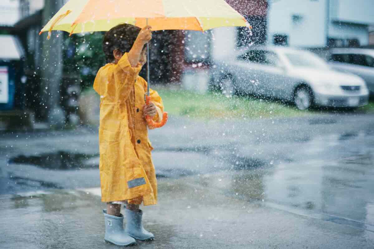 bambino con parapioggia e ombrello 
