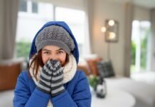 donna infreddolita con abiti invernali all'interno di un salotto
