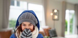 donna infreddolita con abiti invernali all'interno di un salotto