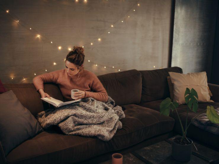 donna seduta su un divano a leggere un libro
